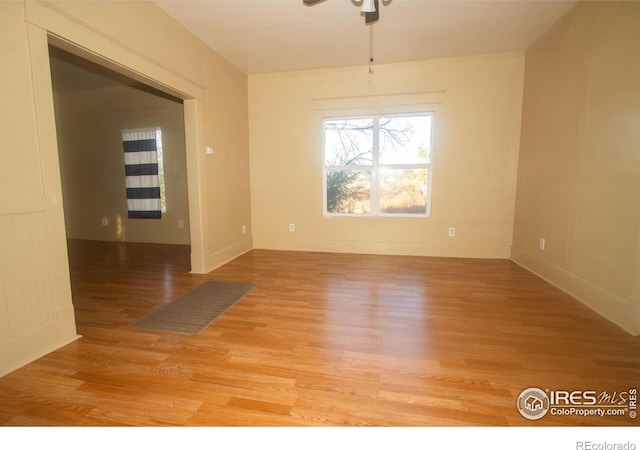 unfurnished room with baseboards, a ceiling fan, and light wood-style floors