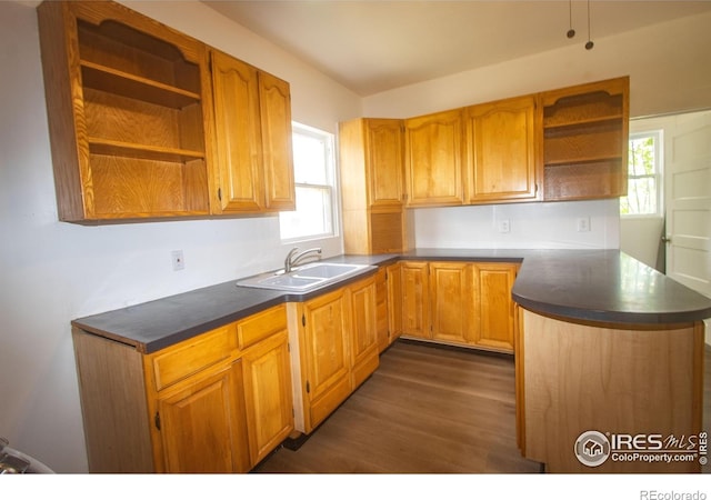 kitchen with a peninsula, open shelves, dark wood-style flooring, a sink, and dark countertops
