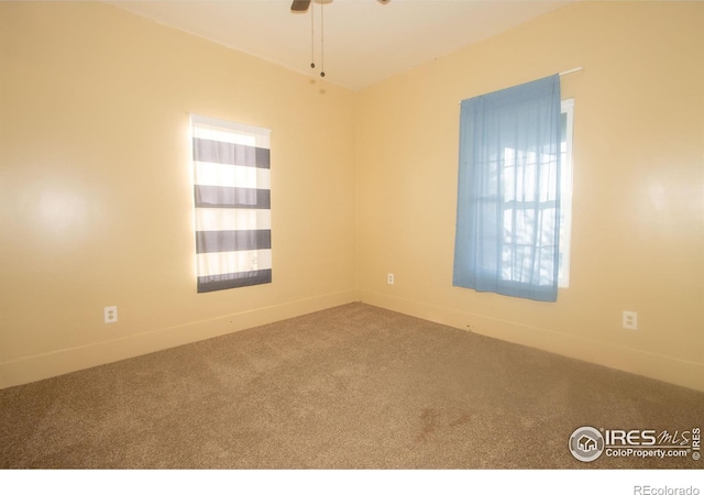 carpeted empty room featuring baseboards and a ceiling fan