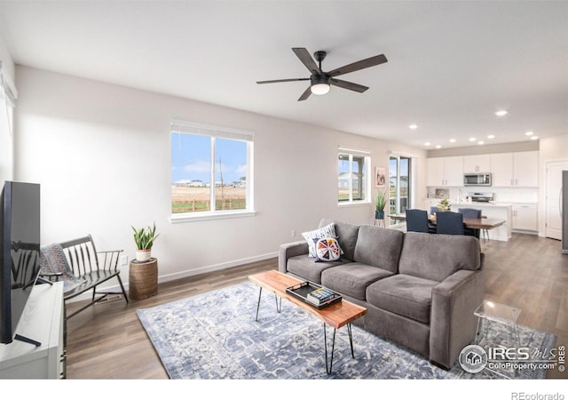 living room featuring light wood finished floors, plenty of natural light, a ceiling fan, and recessed lighting