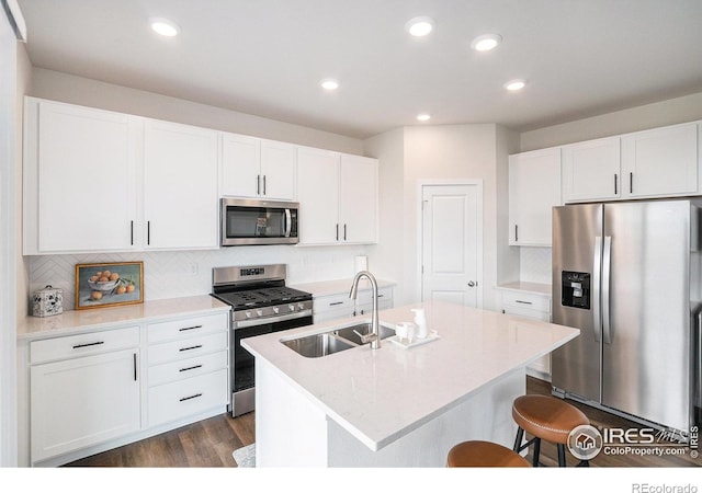 kitchen featuring a sink, white cabinetry, a kitchen breakfast bar, stainless steel appliances, and dark wood-style floors