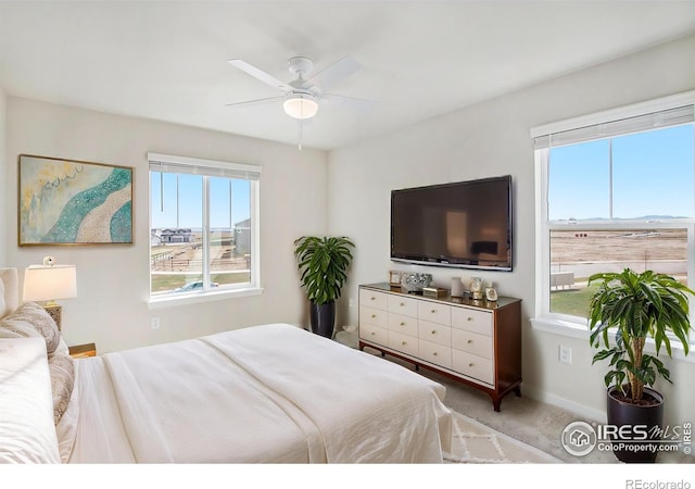 bedroom with multiple windows, baseboards, ceiling fan, and carpet floors