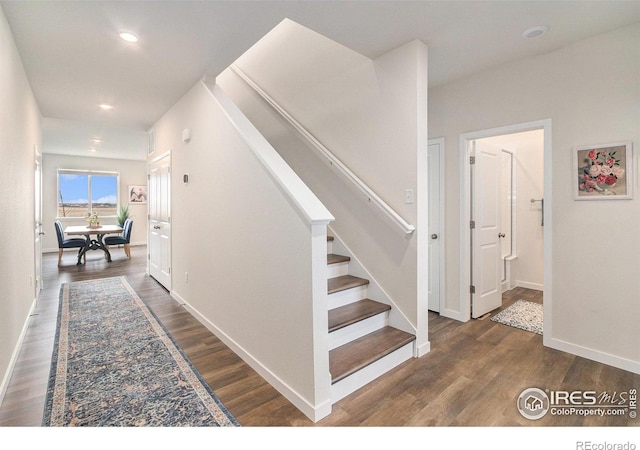 stairway featuring wood finished floors, baseboards, and recessed lighting