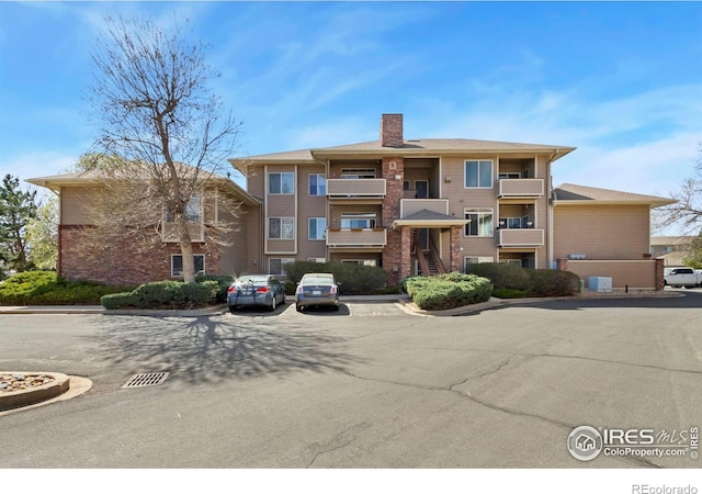 view of property with central AC unit and uncovered parking
