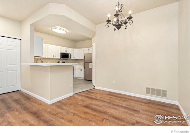 kitchen featuring visible vents, baseboards, an inviting chandelier, appliances with stainless steel finishes, and a peninsula
