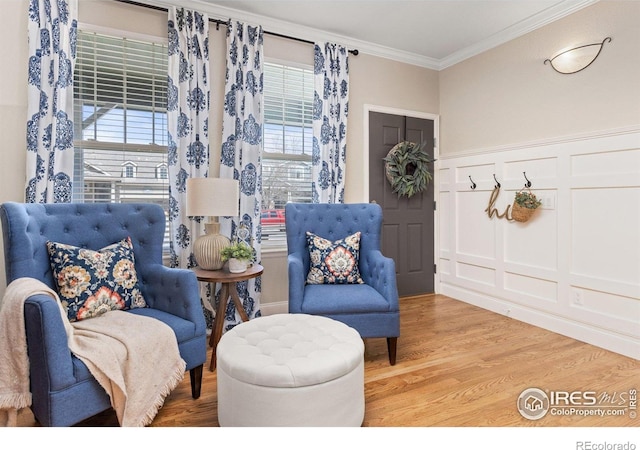 248 Muscovey Ln, Johnstown, CO 80534 - living area with a decorative wall, ornamental molding, light wood-style flooring, and wainscoting