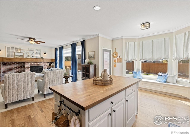 248 Muscovey Ln, Johnstown, CO 80534 - kitchen with light wood-type flooring, ornamental molding, a brick fireplace, open floor plan, and wooden counters