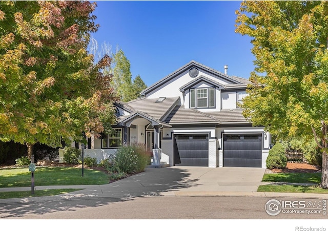 view of front of house with a tile roof, an attached garage, and driveway