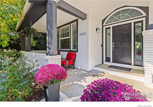 property entrance featuring covered porch and stucco siding