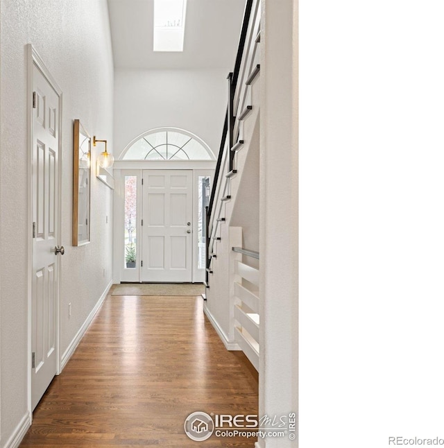 entryway with stairway, a high ceiling, and wood finished floors