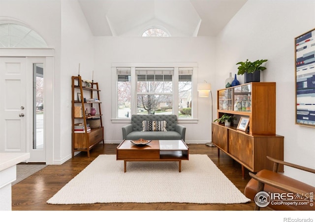 sitting room with baseboards, vaulted ceiling, and dark wood finished floors