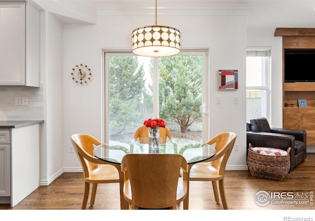 dining space with crown molding, baseboards, and wood finished floors