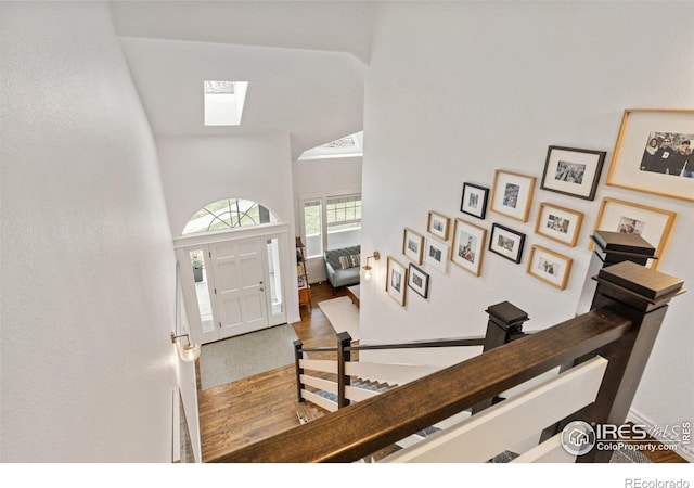 foyer featuring a skylight, wood finished floors, and a high ceiling