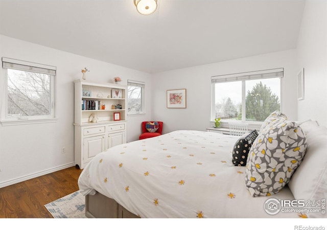 bedroom featuring dark wood finished floors, baseboards, and multiple windows