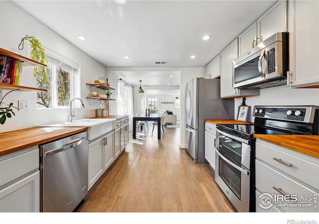 285 Holbrook St, Erie, CO 80516 - kitchen with light wood-style floors, butcher block counters, open shelves, a healthy amount of sunlight, and stainless steel appliances