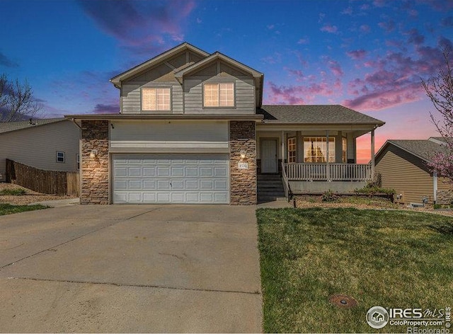 8715 18th Street Rd, Greeley, CO 80634 - traditional-style home featuring stone siding, covered porch, fence, concrete driveway, and a front lawn