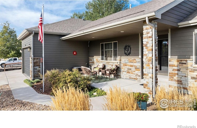 view of front facade with a garage, stone siding, and a shingled roof