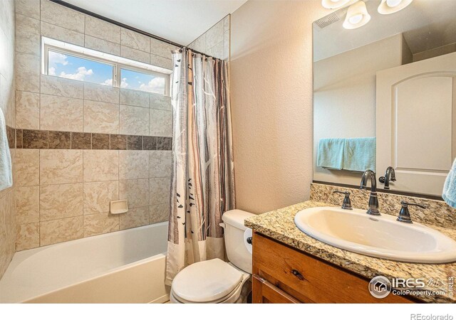 bathroom with toilet, shower / bath combo, vanity, and a textured wall