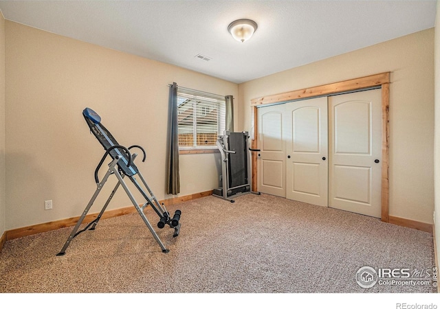 exercise area featuring baseboards, visible vents, and carpet floors