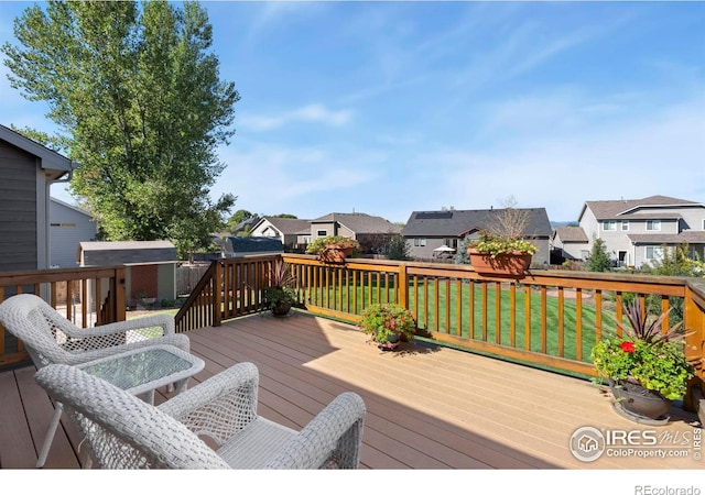 wooden terrace with a yard, an outdoor structure, and a residential view