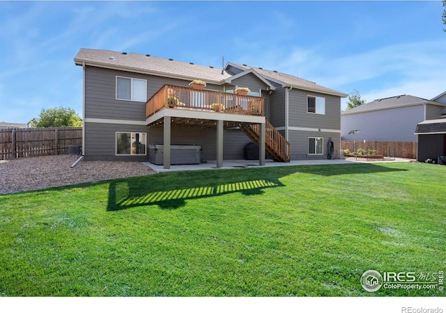 back of house with a hot tub, a yard, a fenced backyard, a patio, and stairs