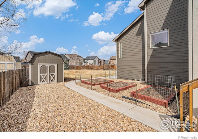 view of yard with a garden, a shed, a fenced backyard, an outdoor structure, and a residential view