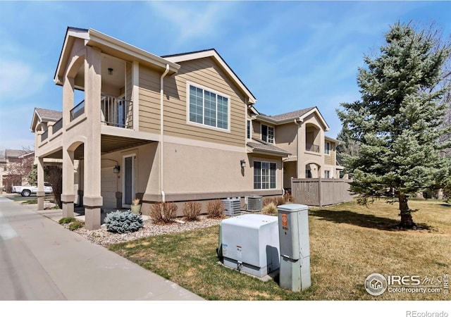 5151 Boardwalk Dr Unit K4, Fort Collins, CO 80525 - view of side of property featuring a lawn, central AC unit, a balcony, and stucco siding