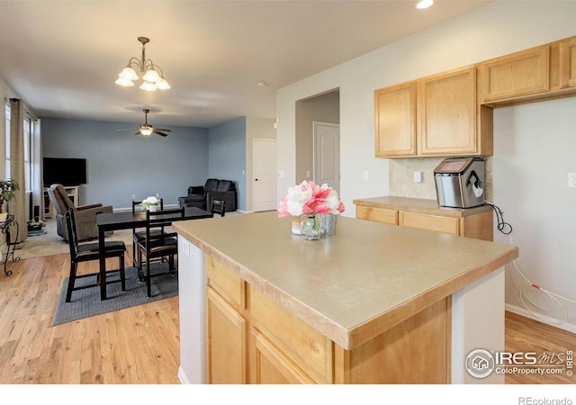 kitchen featuring light wood-style floors, ceiling fan with notable chandelier, light brown cabinetry, and a center island