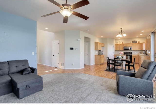 living area with ceiling fan with notable chandelier, light wood-style flooring, visible vents, recessed lighting, and baseboards