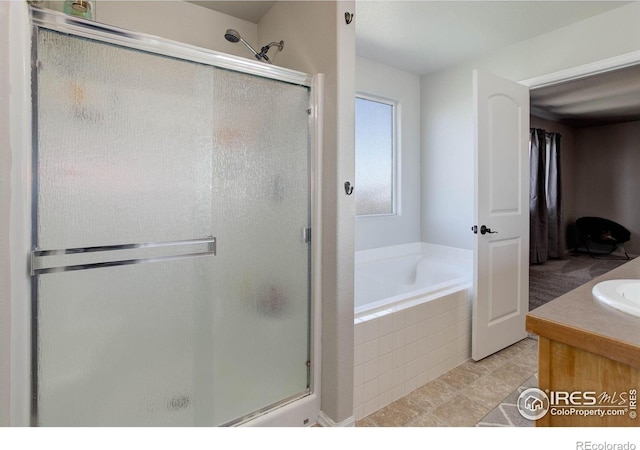 bathroom featuring vanity, a stall shower, tile patterned flooring, and a garden tub