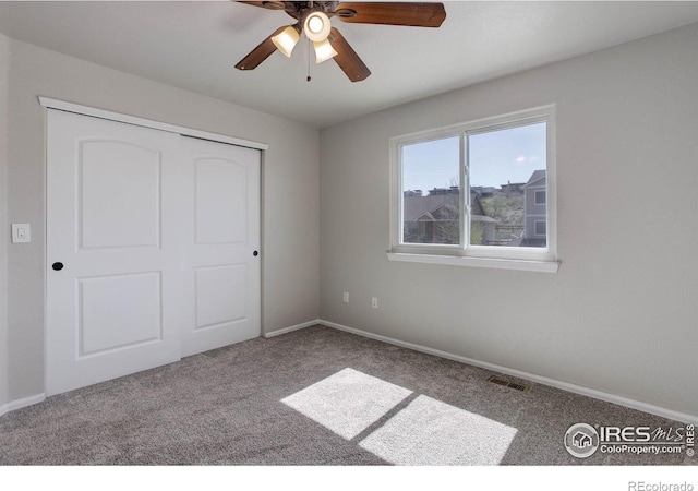 unfurnished bedroom with carpet flooring, visible vents, a closet, and baseboards