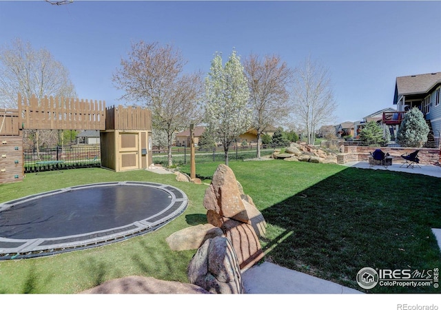 view of yard with a trampoline and fence