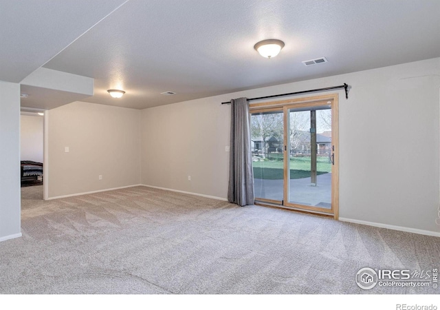 carpeted spare room featuring visible vents, baseboards, and a textured ceiling