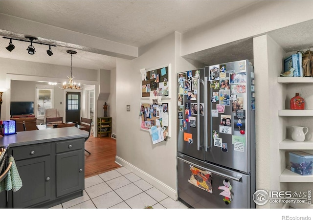 kitchen featuring light tile patterned floors, a textured ceiling, freestanding refrigerator, gray cabinetry, and hanging light fixtures