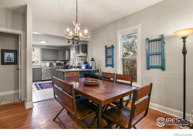 dining space featuring hardwood / wood-style floors, an inviting chandelier, a textured wall, and a textured ceiling