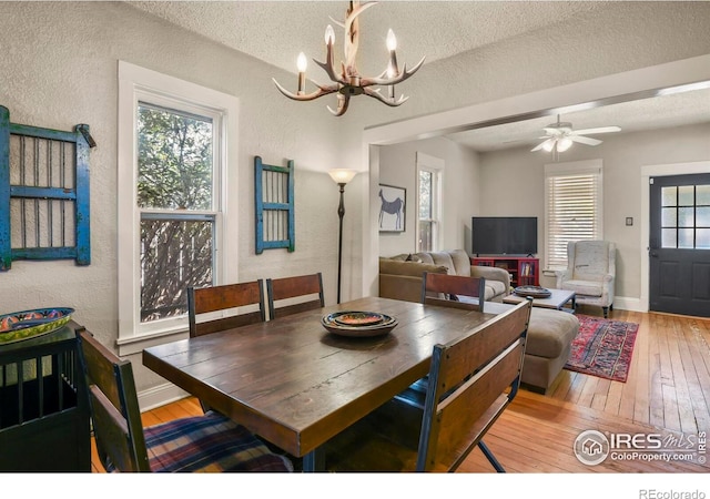 dining space with hardwood / wood-style floors, a chandelier, and a textured wall