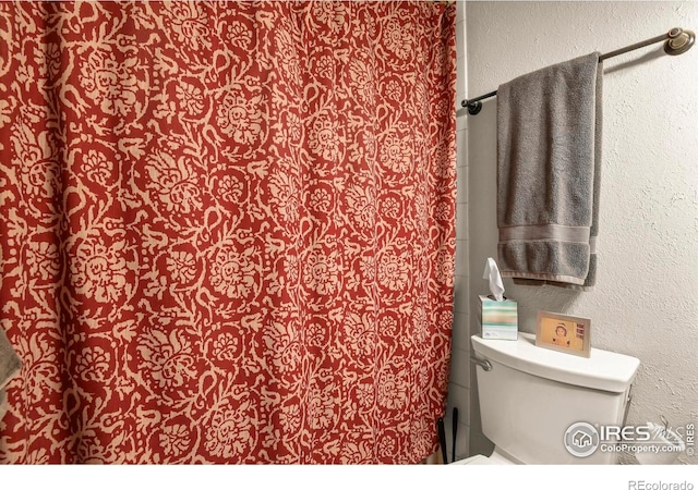bathroom featuring a textured wall and toilet