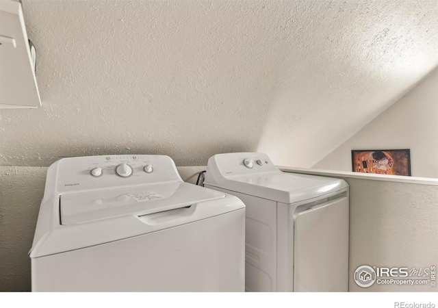 laundry area with a textured wall, washer and clothes dryer, and laundry area