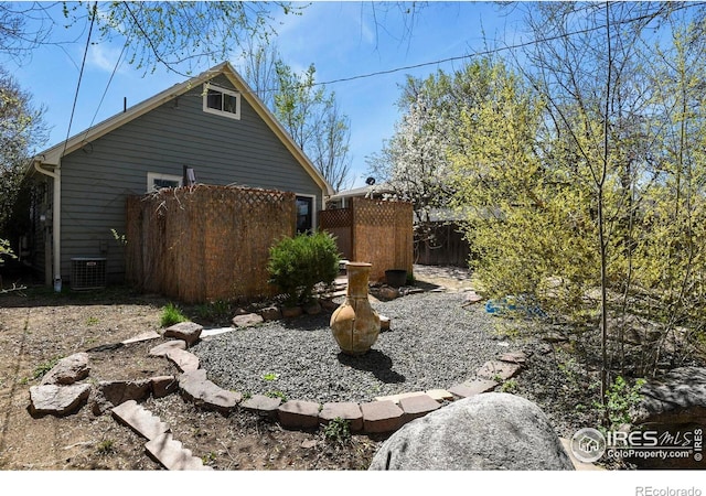 view of property exterior featuring central air condition unit and fence