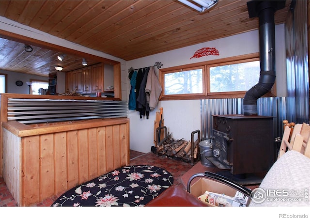 miscellaneous room with brick floor, a wood stove, and wood ceiling