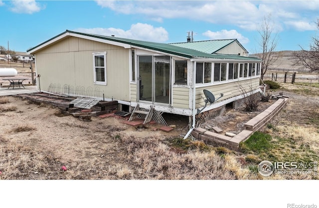 back of property with a sunroom and metal roof