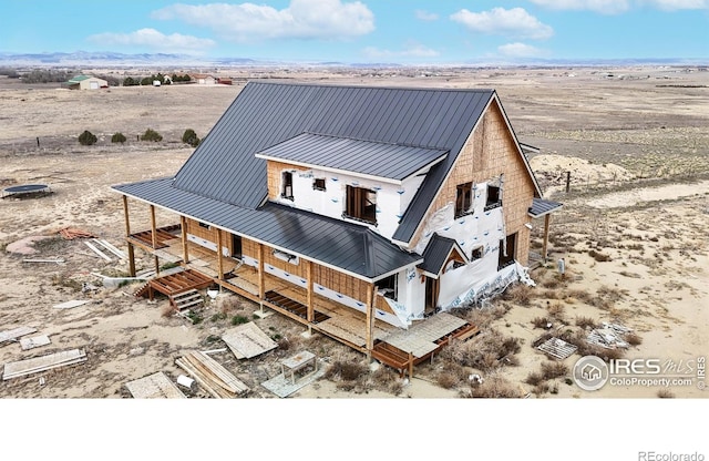 rear view of house with a rural view, metal roof, a standing seam roof, and view of desert