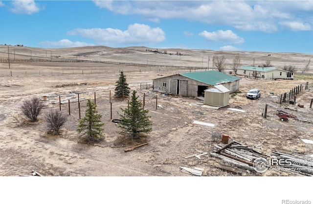 view of yard featuring a rural view, fence, and an outdoor structure