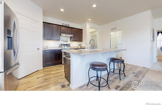 3712 Daylily St, Wellington, CO 80549 - kitchen featuring a sink, appliances with stainless steel finishes, a kitchen bar, light wood-style floors, and under cabinet range hood