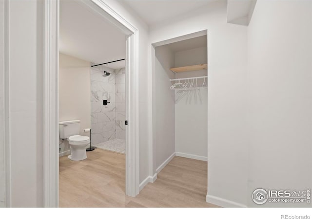 bathroom with a shower stall, baseboards, toilet, and wood finished floors