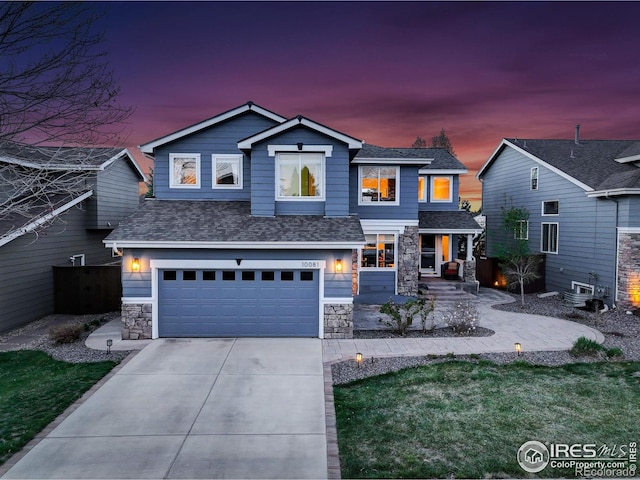 view of front of home featuring a shingled roof, driveway, stone siding, and an attached garage