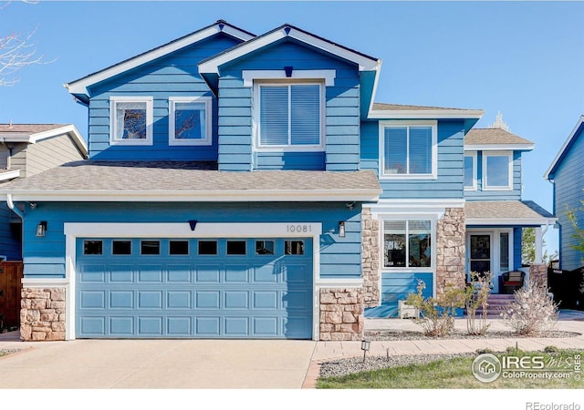 view of front of home featuring roof with shingles, driveway, stone siding, and an attached garage