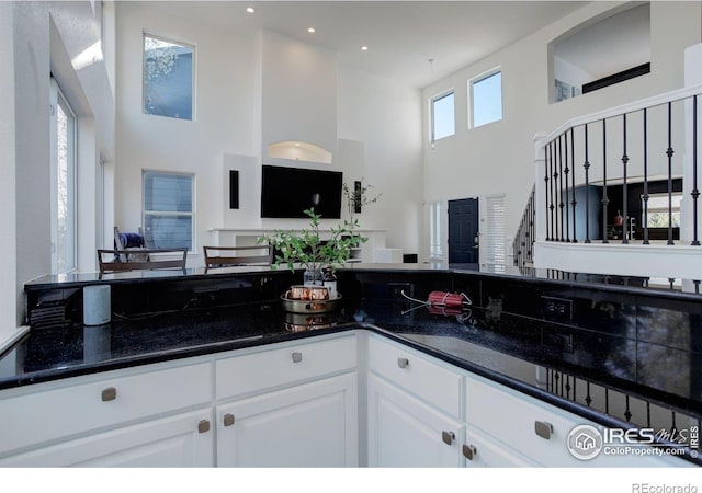 kitchen featuring white cabinets, open floor plan, and a high ceiling