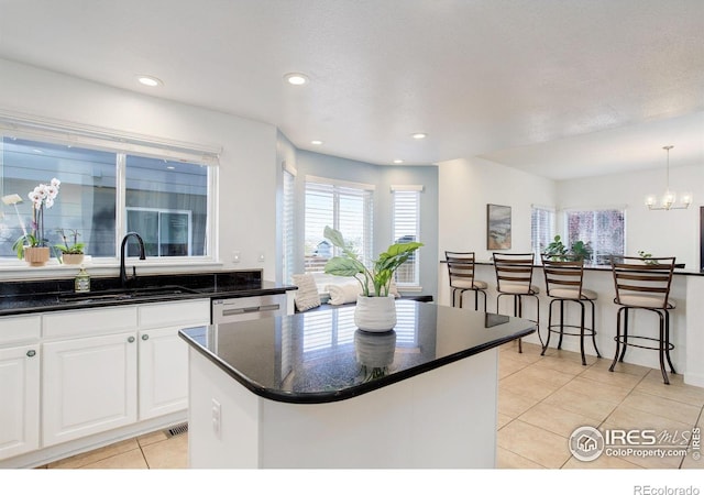 kitchen featuring a healthy amount of sunlight, light tile patterned floors, a sink, and stainless steel dishwasher