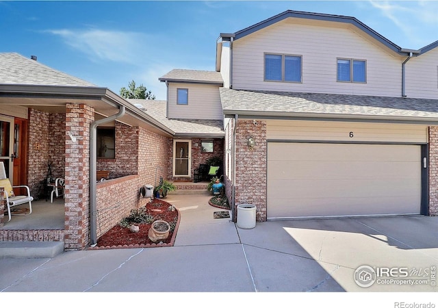 traditional-style house with brick siding, driveway, an attached garage, and a shingled roof